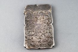 A small silver card case with profuse engraved scroll decoration to the shaped case,