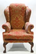 A wing back armchair on carved cabriole legs with claw and ball feet,
