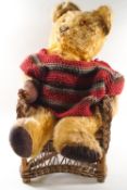 A Teddy bear on a wicker chair wearing a knitted jumper,