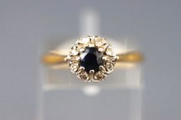 A yellow and white metal cluster ring set with a sapphire and surrounded by single cut diamonds.