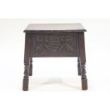 An oak sewing table, the hinged cover above a grape carved frieze on turned legs,