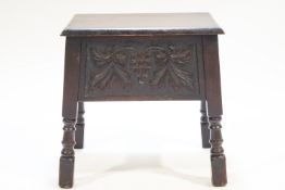 An oak sewing table, the hinged cover above a grape carved frieze on turned legs,