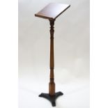 A pine lectern on turned support and triform cast iron base,