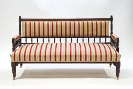 An Edwardian mahogany spindle back sofa with reed and floral striped upholstery