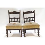 A pair of Edwardian nursing chairs with bobbin turned splats above a over stuffed seats,