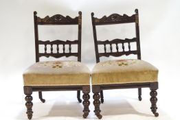 A pair of Edwardian nursing chairs with bobbin turned splats above a over stuffed seats,