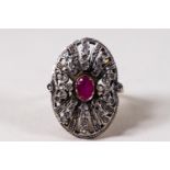 A yellow and white metal large oval dress ring set with a central oval faceted ruby.
