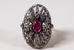 A yellow and white metal large oval dress ring set with a central oval faceted ruby.