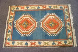 A knotted wool carpet with two central medallions on a blue ground in a similarly decorated border,