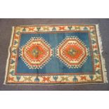 A knotted wool carpet with two central medallions on a blue ground in a similarly decorated border,