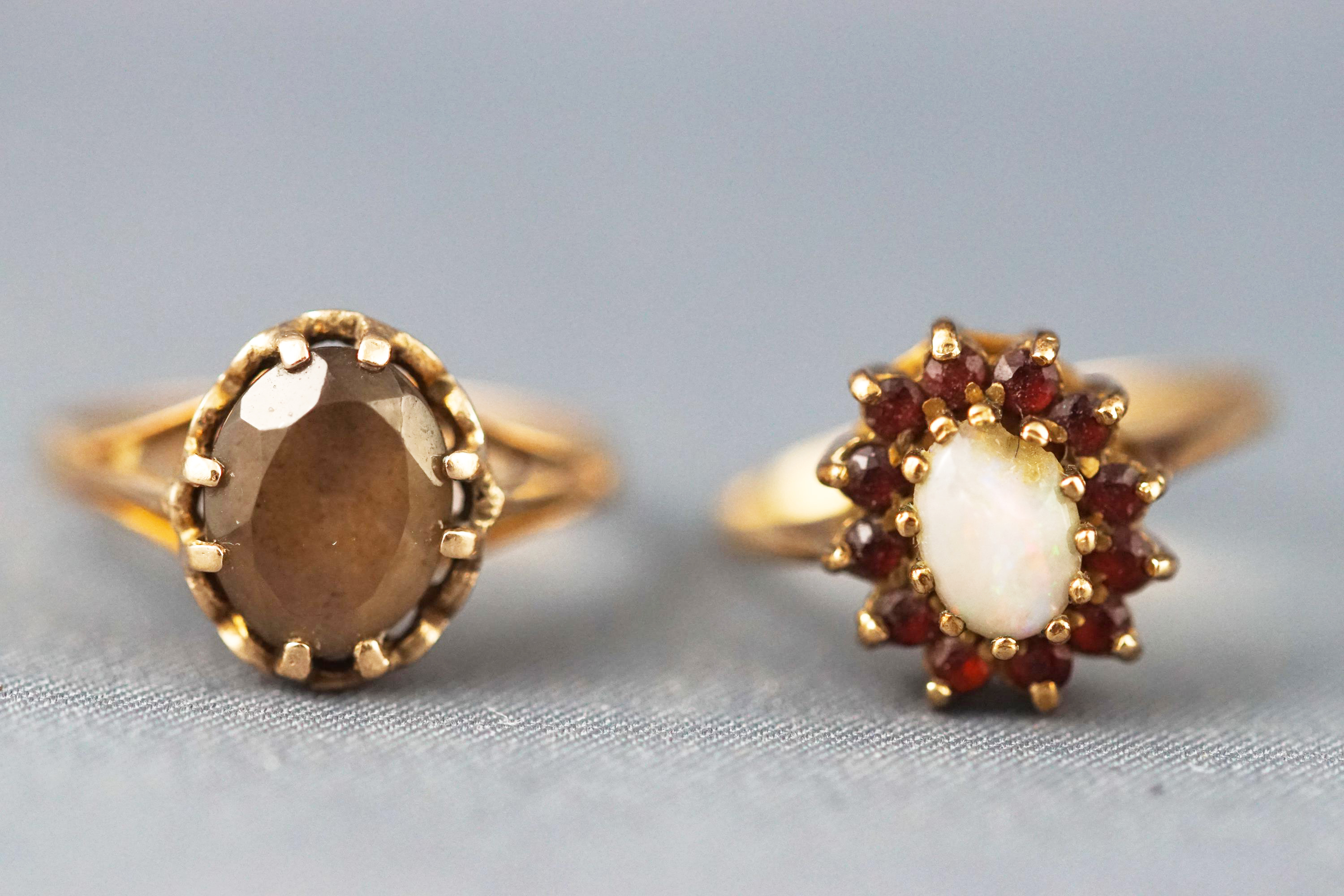 A yellow metal opal and garnet cluster ring together with a yellow metal single stone quartz ring.