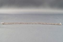 A white metal diamond line bracelet. Illusion set with forty four round brilliant cut diamonds.