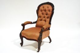 A Victorian mahogany show frame armchair with button back and carved cabriole legs