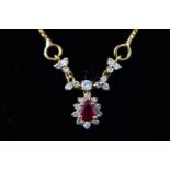 A yellow metal centrepiece necklace set with a pear cut ruby and surrounded by diamonds.