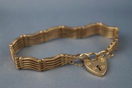 A yellow metal wavy bar/gate bracelet, padlock and safety chain.