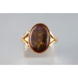 A yellow metal single stone ring set with a brown shallow cabochon agate stone measuring 16.