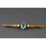 A yellow metal bar brooch set with an oval faceted aquamarine and two seed pearls..