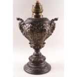 A French Spelter oil lamp with two mask handles and flared base,