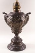 A French Spelter oil lamp with two mask handles and flared base,