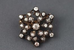 An Edwardian yellow and white metal floral brooch set with variable sized old cut diamonds.