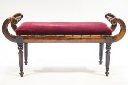 A William IV mahogany window seat, with carved and turned scroll ends on turned tapering legs,