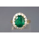 A yellow and white metal cluster ring set with an oval emerald.