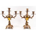 A pair of brass rococo style candlesticks, each with three branches,