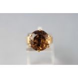 A yellow metal dress ring set with a large round faceted cut smoky quartz. Tests indicate 9ct gold.