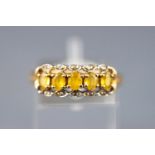 A yellow metal dress ring set with five yellow beryl and diamonds. Hallmarked 9ct gold, Sheffield.