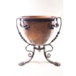 An Arts and Crafts style planter in the form of a copper bowl in a wrought iron stand,
