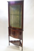 An Edwardian mahogany corner cabinet with bow fronted glazed door with blind fret work,