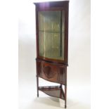 An Edwardian mahogany corner cabinet with bow fronted glazed door with blind fret work,