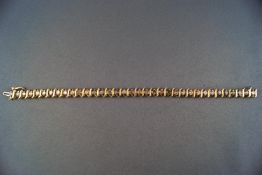 A yellow metal diamond line bracelet set with thirty five round brilliant cut diamonds.