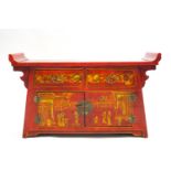 A red Japanned Chinese style Altar table with two drawers above two cupboard doors,