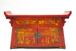 A red Japanned Chinese style Altar table with two drawers above two cupboard doors,