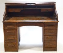 An oak roll top desk with eight drawers flanking a central drawer,