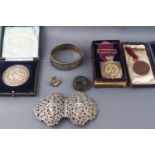 An Asian white metal belt buckle, a silver and gilt buffaloes medal and two others,