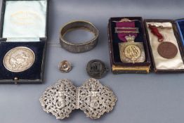 An Asian white metal belt buckle, a silver and gilt buffaloes medal and two others,