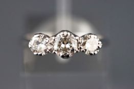 A white metal diamond ring set with three transitional cut diamonds.