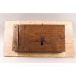 An 18th century iron lock with key, encased in oak on a plywood board