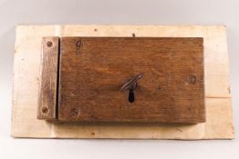 An 18th century iron lock with key, encased in oak on a plywood board