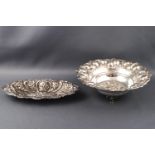 Two Continental metal bon bon dishes with repousse floral decoration, one raised on three feet,