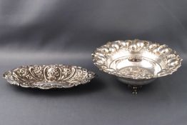 Two Continental metal bon bon dishes with repousse floral decoration, one raised on three feet,
