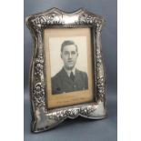 An Edwardian silver shaped and floral swag decorated rectangular photograph frame with green velvet