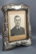 An Edwardian silver shaped and floral swag decorated rectangular photograph frame with green velvet