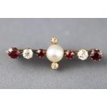 A yellow metal brooch set with a central pearl together with old cut diamonds and garnets.