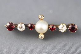 A yellow metal brooch set with a central pearl together with old cut diamonds and garnets.