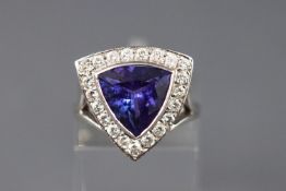 A white metal dress ring set with a triangular faceted cut tanzanite
