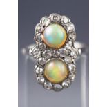 A white metal dress ring set with two circular cabochon opals together with twenty three diamonds.