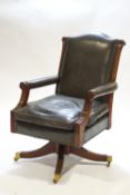 A mahogany framed green leather swivel chair, raised on four splayed legs on casters,